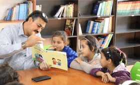 Mohammad, a Syrian refugee, reading to children in Azarq camp, Jordan