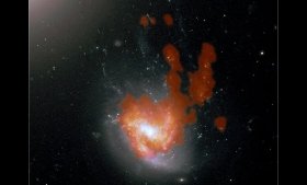 A Hubble Space Telescope image of NGC 4858, showing the stellar tendrils extending north from the barred spiral disk. The cold molecular gas in NGC 4858, seen by the ALMA radio telescope with its “bunny ear” inner tail, is shown in orange.