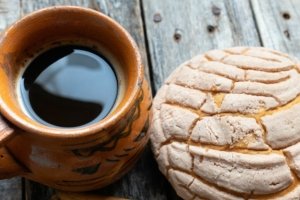 A cup of coffee with a concha bread