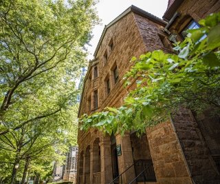 A brown brick building surrounded by greenery.