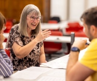 Three people sit around a table conversing in Dow Hall.