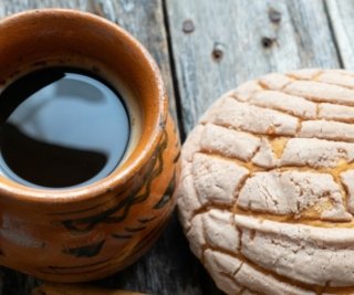 A cup of coffee with a concha bread