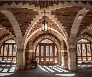 The loggia of Yale's Humanities Quadrangle, a bright, brick-walled space with arched ceilings.