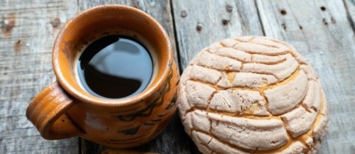 A cup of coffee with a concha bread