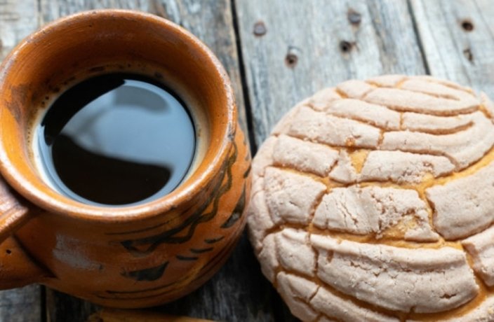 A cup of coffee with a concha bread