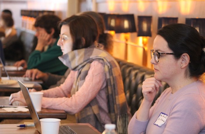 Faculty writing at individual tables