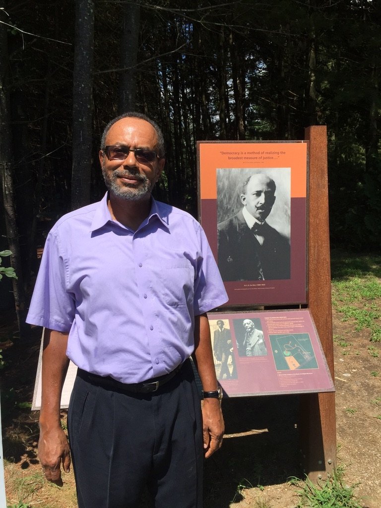 Gooding-Williams standing in front of a plaque featuring W. E. B DuBois.