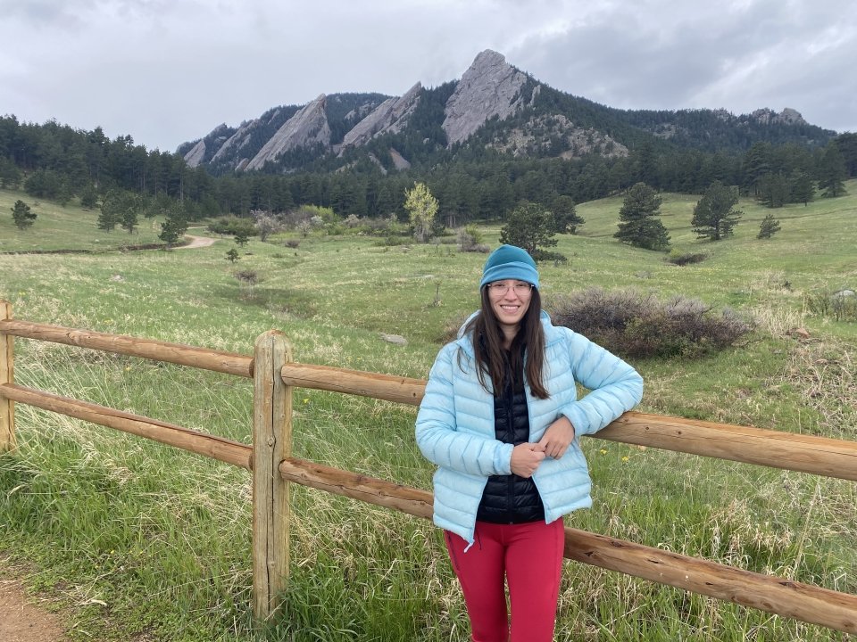 Yankovsky stands in front of a green meadow with mountains in the background at Chautauqua in Boulder, Colorado.