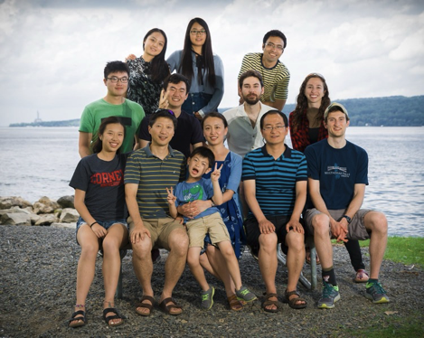 Ke and members of his lab posing for a portrait on a beach.