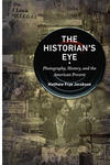 Book cover, showing a camera lense superimposed to old photographs in sepia. 