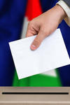 Picture of a hand casting a vote into a voting booth. 