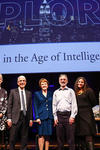 Portrait of Catharine Bond Hill, President Peter Salovey, Margaret Warner, Shelly Kagan, Laurie Santos, and Brian Scassellati. They stand on a stage and behind a collosal sign reads "Explores. Being Human in the Age of Intelligent Machines."